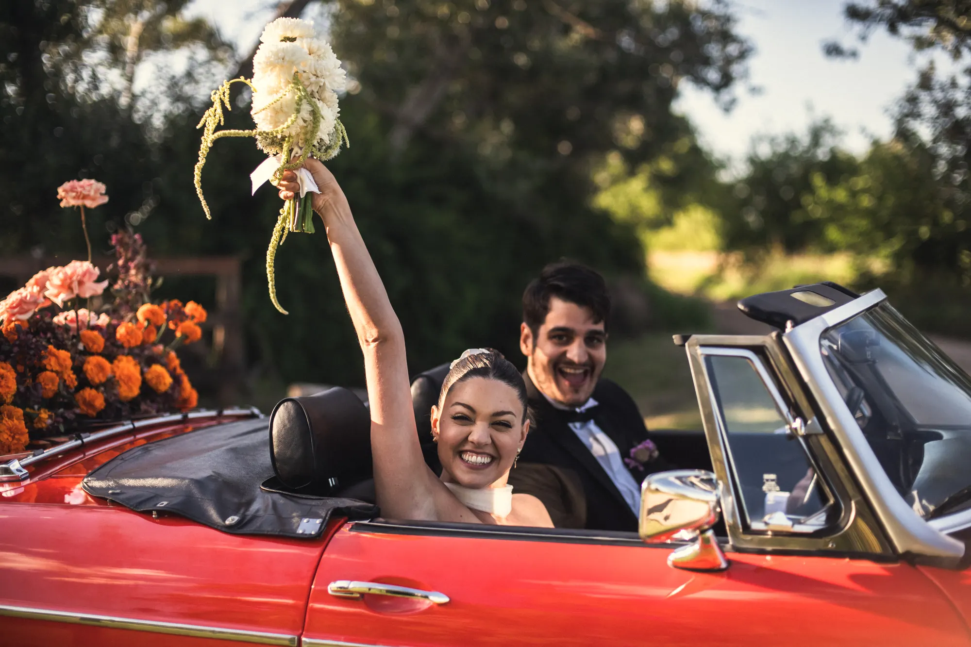 Couple celebrating from a classic red convertible